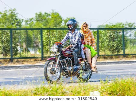 Mother, Father And Small Child Riding On Scooter Through Busy Highway