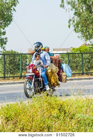 Mother, Father And Small Child Riding On Scooter Through Busy Highway