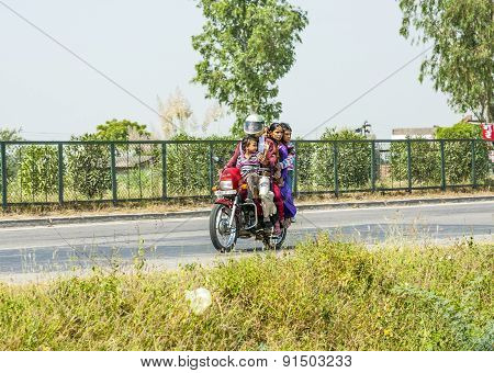 Mother, Father And Small Child Riding On Scooter Through Busy Highway