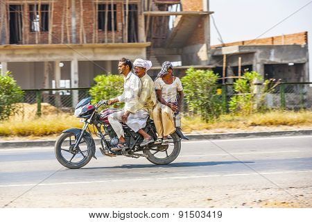 Mother, Father And Son Riding On Scooter Through Busy Highway