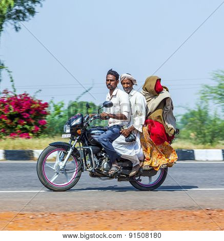Mother, Father And Small Child Riding On Scooter Through Busy Highway