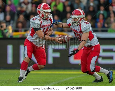 GRAZ, AUSTRIA - MAY 31, 2014: QB Kasper Skyum Jensen (#14 Denmark) hands off the ball to RB Lars Hyrsting Larsen (#18 Denmark) in match against Austria during the EFAF European Championships 2014 in Austria.