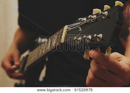 Man tuning electric guitar
