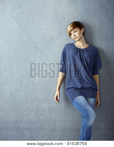 Attractive young woman leaning to wall daydreaming