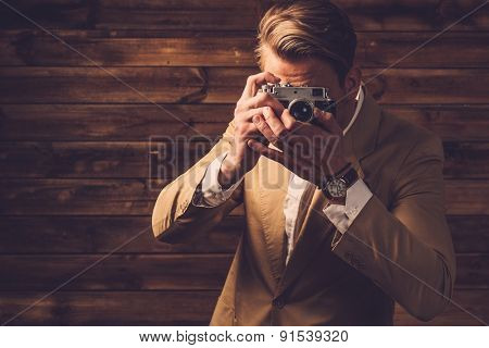Stylish man with retro camera in rural cottage interior 