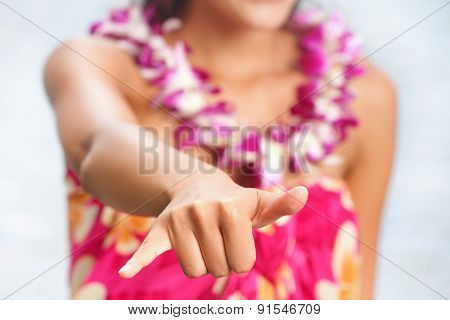 Hawaii beach woman making Hawaiian shaka hand sign wearing lei of flowers. Hawaii, USA.