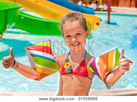 Child with colored armbands playing in swimming pool. Summer outdoor.