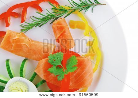 smoked salmon slices with vegetabls over white plate