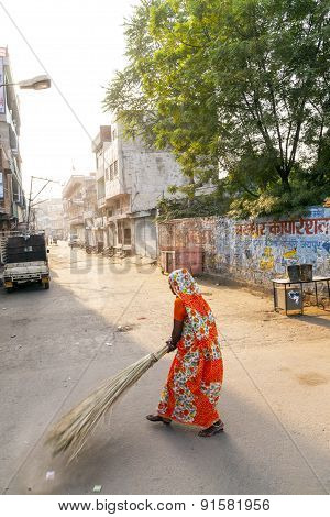 Woman Of Fourt Class In Brightly Colored Clothing Cleans The Street