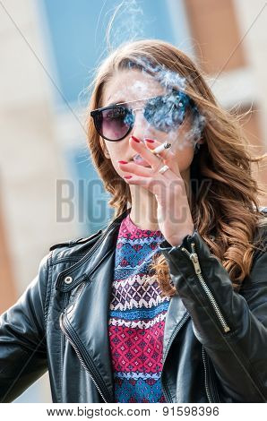 Beautiful female smoking a cigarette with smoke in front of face.