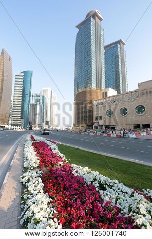 DOHA, QATAR - FEBRUARY 17, 2016: Municipal flowerbeds beside the City Centre mall and hotels in Dafna, with labourers are hard at work.