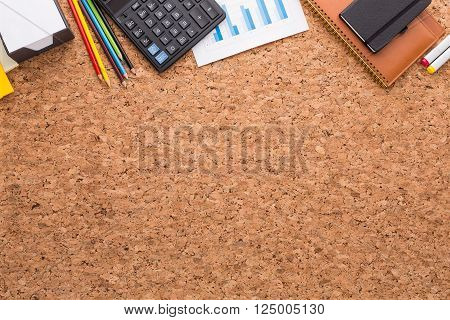Cork table notebooks graphs calculator and pencils on it. Top view. Concept of work.
