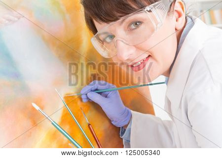 Artwork conservator at work with old painting wearing protective suit