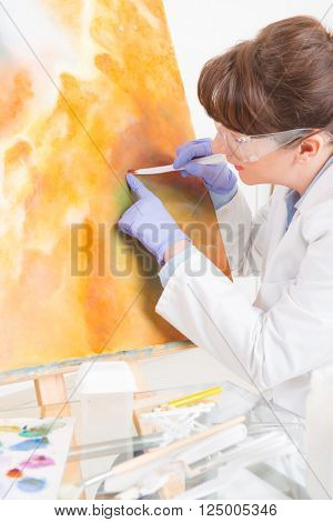 Artwork conservator at work with old painting wearing protective suit