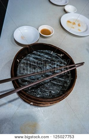 Traditional chinese food, steamed dumpling served on table in a wooden dish and with wooden chopsticks.
