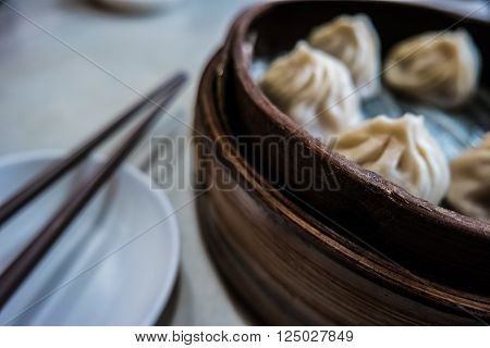 Traditional chinese food, steamed dumpling served on table in a wooden dish and with wooden chopsticks.