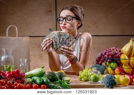Dispirited young woman counting money for buying expensive natural food. High price of healthy natural food