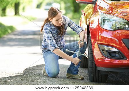 Frustrated Female Motorist Trying To Change Wheel On Country Road
** Note: Shallow depth of field