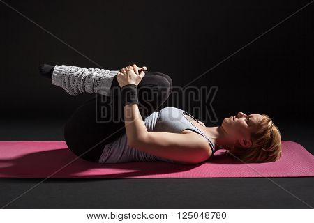 Young woman practicing yoga, Pawanmuktasana / Wind Relieving pose