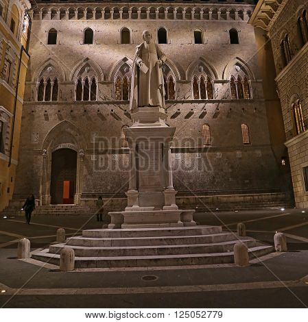 SIENA ITALY - MARCH 11 2016: Sallustio Bandini on Piazza Salimbeni at night Siena Tuscany - Italy.