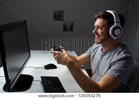 technology, gaming, entertainment, let's play and people concept - happy young man in headset with controller gamepad playing computer game at home and streaming playthrough or walkthrough video
