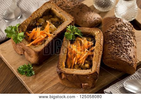 Fresh pea soup in a Bread Bowl, on a wooden board with salt and papper