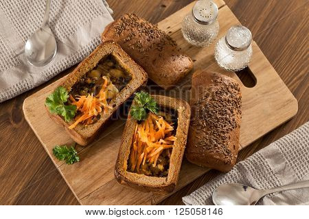 Fresh pea soup in a Bread Bowl, on a wooden board with salt and papper