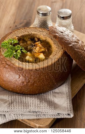 Fresh pea soup in a Bread Bowl, on a wooden board with salt and papper