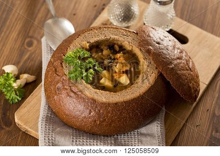 Fresh pea soup in a Bread Bowl, on a wooden board with salt and papper