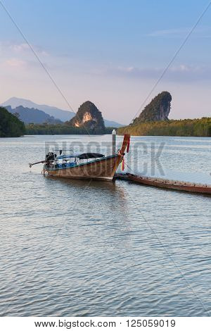 Sunset view of Krabi River with long-tail boat and limestone karst cliffs Krabi Town Thailand