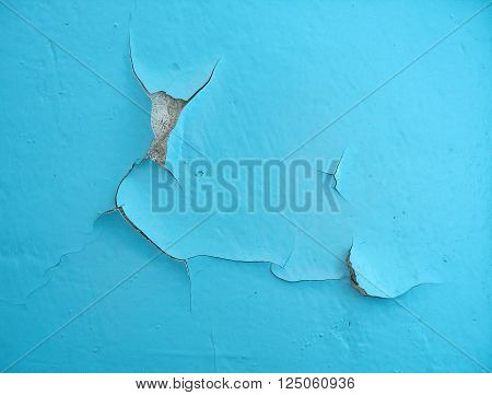 Close-up of blue cracked paint on the wall. Old weathered painted wall surface. Grunge background with vintage paint