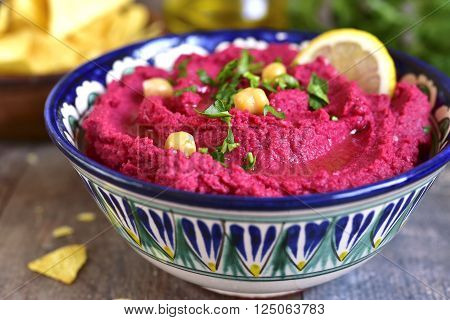 Beetroot hummus in a colorful bowll on a wooden table.
