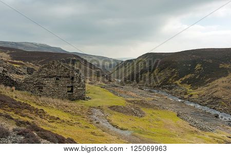 Spring sunshine breaks through cloud to shine on a ruined smelting mill works at Surrender Bridge, Swaledale, Near Reeth, Yorkshire Dales National Park