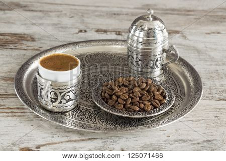 Turkish coffee with traditional presentation and coffee beans on wooden background.