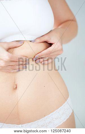 Woman dressed in white showing her abdomen localized fat