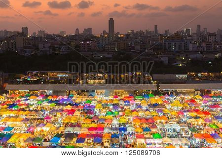 Aerial view colourful flea market roof top with city downtown background during sunset