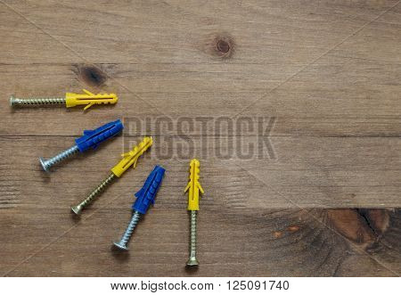 screws with blue and yellow dowels on old wooden table