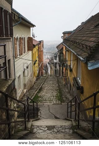 Old medieval narrow stone paved street in Buda district of of Budapest on a foggy day in winter. Shot at Gul Baba utca