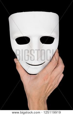 Hand holding a white mask on the black background.