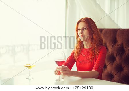 Portrait of a smiling young woman holding a glass of red wine.