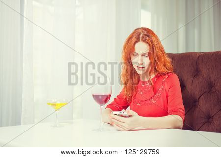 Beautiful girl talking on the phone in a cafe and drink wine.