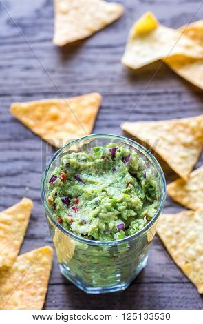 Guacamole with tortilla chips on the wooden table