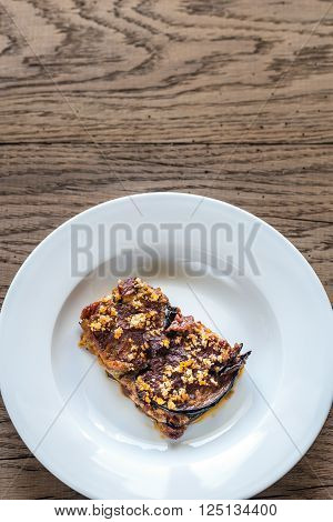 Portion of Parmigiana di melanzane on the wooden background