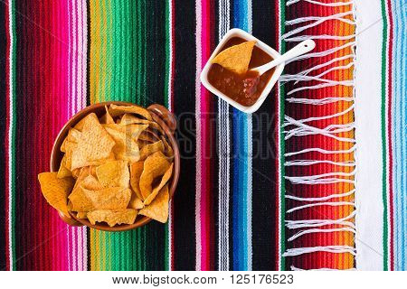 Nachos chips and tomato sauce over a colored poncho seen from above