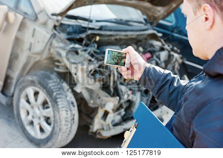 Insurance agent photographing car damage for claim form