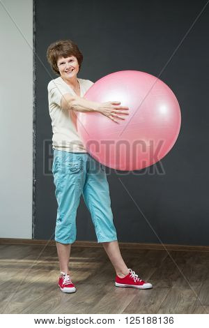 Smiling fit aged lady with exercise ball