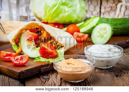 Fried chicken meat with vegetables in pita bread. Selective focus.