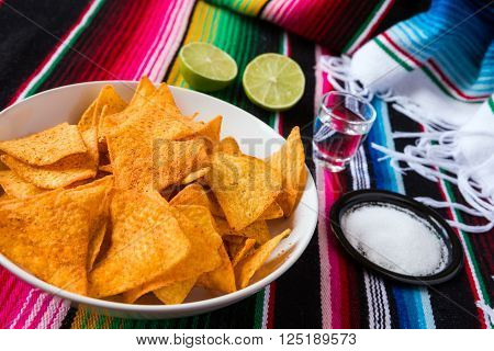 Nachos chips in a bowl tequila lime and salt over a colored poncho
