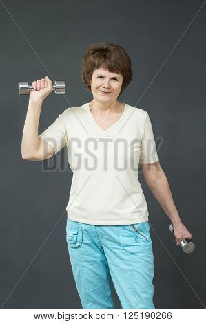 Smiling fit aged lady with exercise dumbbells
