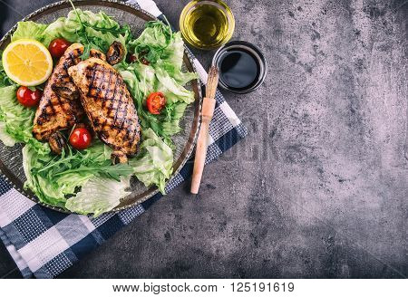 Grilled chicken breast in different variations with lettuce salad cherry tomatoes .mushrooms herbs cut lemon on a wooden board or grill pan. Traditional cuisine. Grill kitchen.